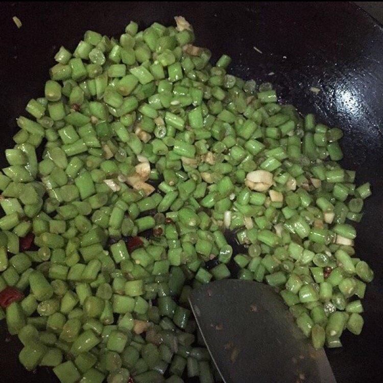 肉末四季豆,放入四季豆煸炒,边加水边炒,大概要五分钟才能炒熟(不熟有毒哦)中途不能盖锅盖会焖黄的