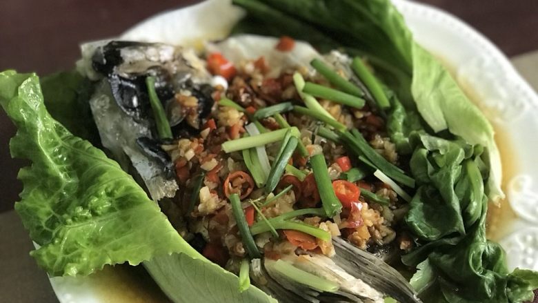 剁椒鱼头,第5分钟时，将生菜摆在鱼头两边，摆盘，淋上麻油，洒上葱段，盖上盖，1分钟后关火