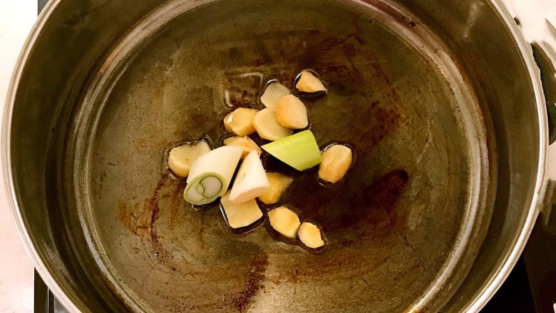 五花肉烧萝卜,锅里加入大豆色拉油,烧热后加入大葱段和姜片翻炒1分钟