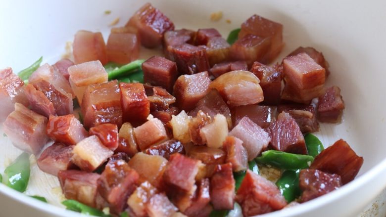 甜酒糟炒腊肉,放入腊肉块,转中火煸炒至腊肉丁微焦出香味。