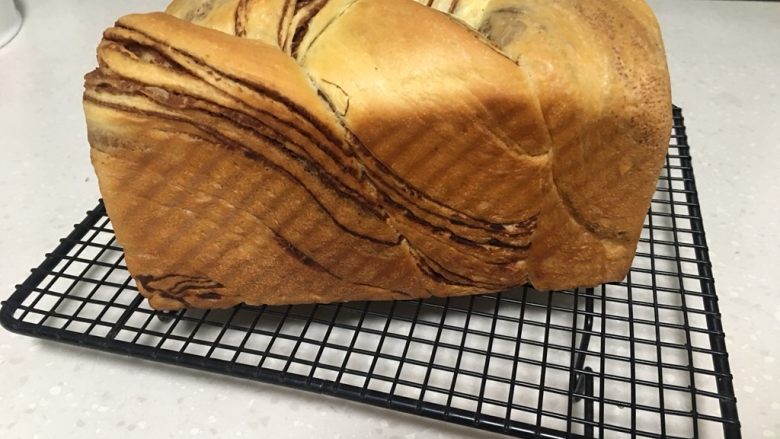 大理石纹豆沙吐司,烤箱预热后,设置170上火、155度下火,中层烘烤35分钟即可脱模出炉。烘烤15分钟左右表皮变黄后要加盖锡纸继续烘烤。