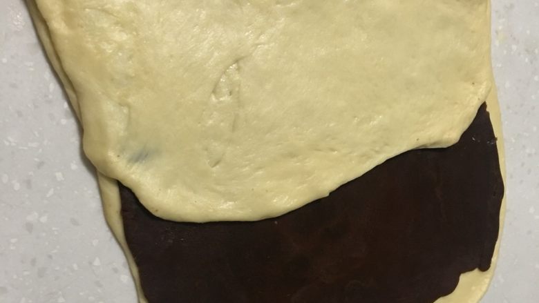 大理石纹豆沙吐司,叠被子的方法将空白面皮叠起来,盖住豆沙面皮的一半。