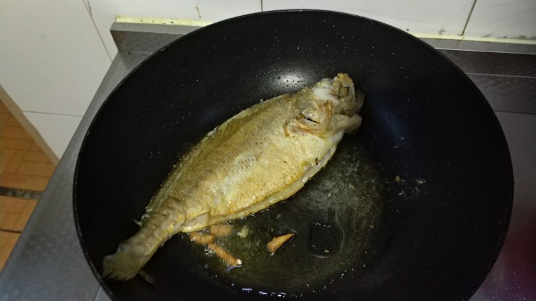 砂锅鱼炖豆腐,煎鱼。油烧热后放入姜丝,鱼两面煎至金黄。取出备用。