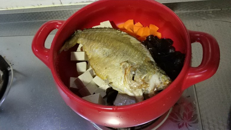 砂锅鱼炖豆腐,把豆腐木耳胡萝卜放入锅中,再在上面放煎好的鱼,倒入料酒,清水。中火加热至沸腾后,转小火煮30分钟。