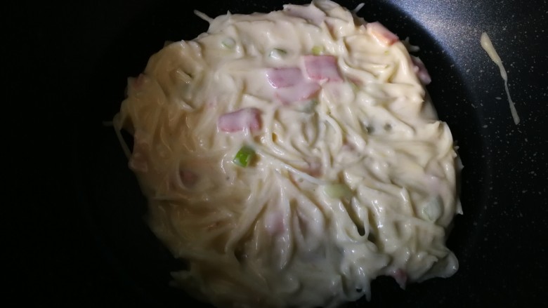 #圆土豆#培根土豆丝煎饼,放入平底锅里,摊平。