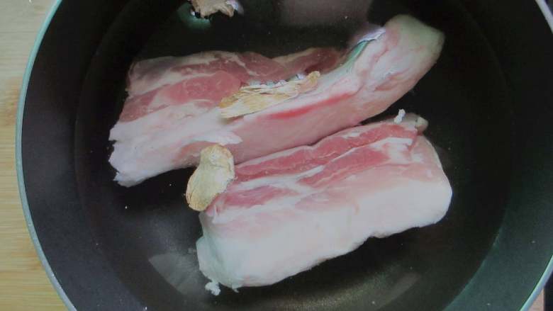 千张结烧肉,、锅中放入料酒、姜片,下入五花肉焯水