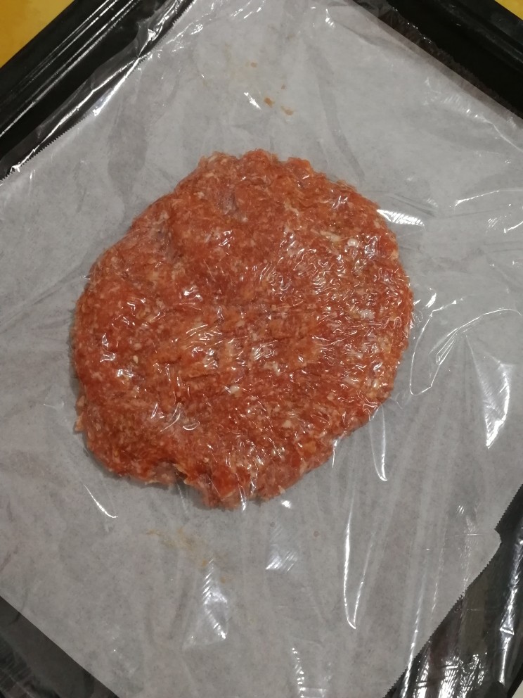 叉烧猪肉脯,烤盘铺上油纸,放入肉团,盖上保鲜膜,压扁。