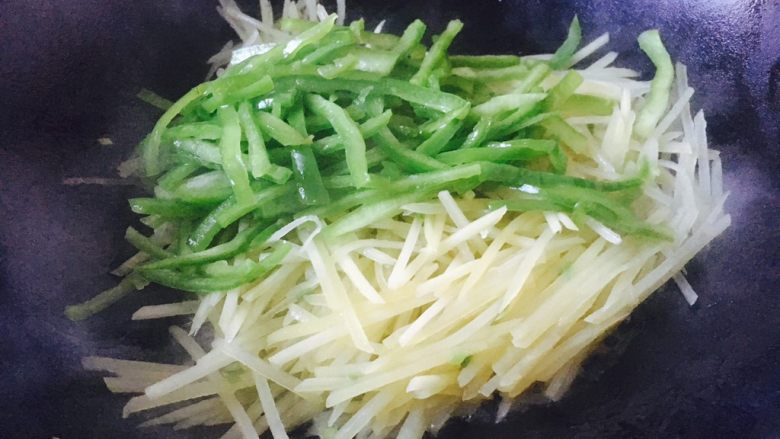 #圆土豆# 花椒油青椒土豆丝,土豆丝炒至九成熟时放入青椒丝,翻炒均匀。