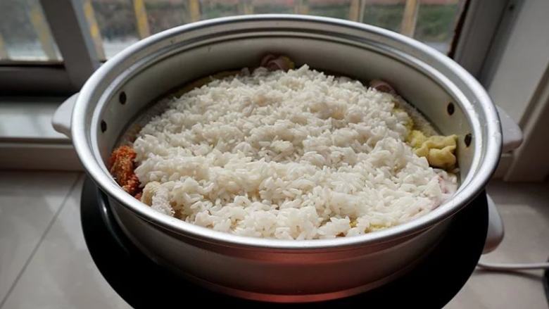 糯米鲜肉煎饼,蒸锅里放一块湿布,把泡好的糯米放入蒸锅里,用手摊平,开始蒸