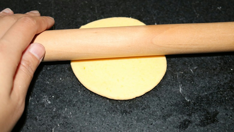 ≈南瓜豆沙包≈,取一个面团揉成圆球状,用手压一下,擀成圆形