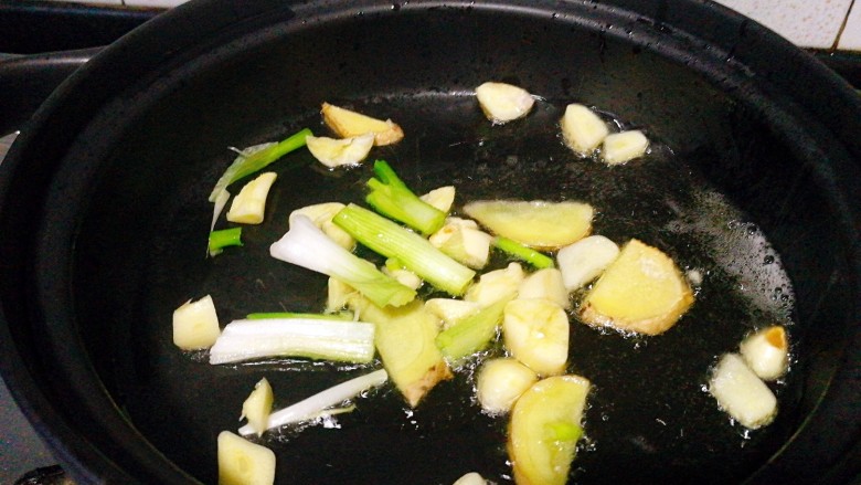 圆土豆+鸡翅塔吉锅,把锅润下油把蒜瓣和姜片,葱白段加入,煸香关火!
