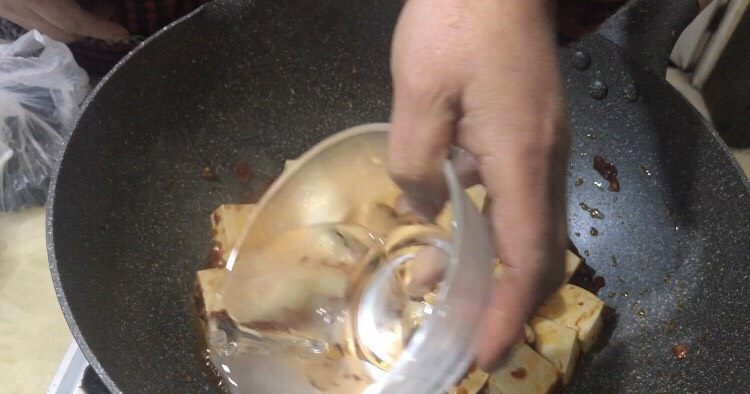 家常版麻婆豆腐,放盐煸炒后加水,淹没豆腐底部。