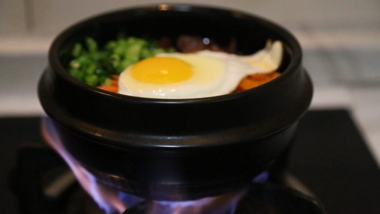 腊肠石锅拌饭,放上炒好的香菇/腊肠/青菜/胡萝卜和准备好的韩式辣萝卜,放在炉子上小火加热至米饭四周出现焦黄香气即可。