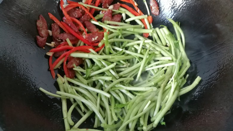 腊肠炒泥蒿,接着下入泥蒿,翻炒均匀;