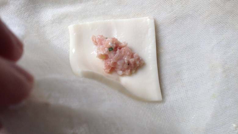 豆腐饺子,然后把肉馅放在豆腐片上(注意肉馅不能放多),再提起纱布一个角,对角折过去盖住肉馅