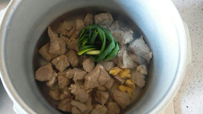 园土豆+咖喱土豆炖牛腱,切小块抄水后将牛腱倒入高压锅里,放入姜,葱和料酒。加入水,水量没过牛肉,盖上盖子大火煮到上汽后转中火,煮25分钟。