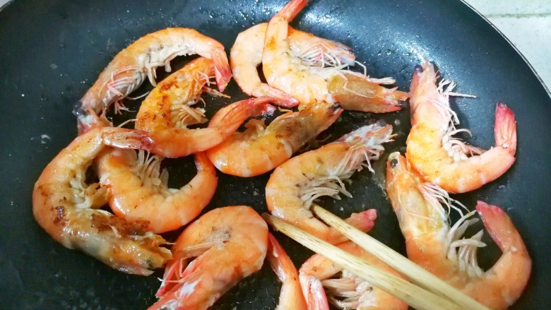 中西结合的黄油香煎孜然大虾,底面煎焦后,用筷子翻面,继续煎制另一面,