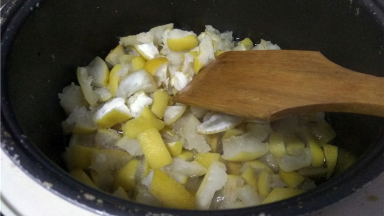 柚子皮糖,加盖,开启“煮饭”程序,观察电饭煲冒烟,揭开盖子,放入挤干水分的柚子皮,搅拌均匀(冰糖、白糖融化后,再倒入柚子皮);