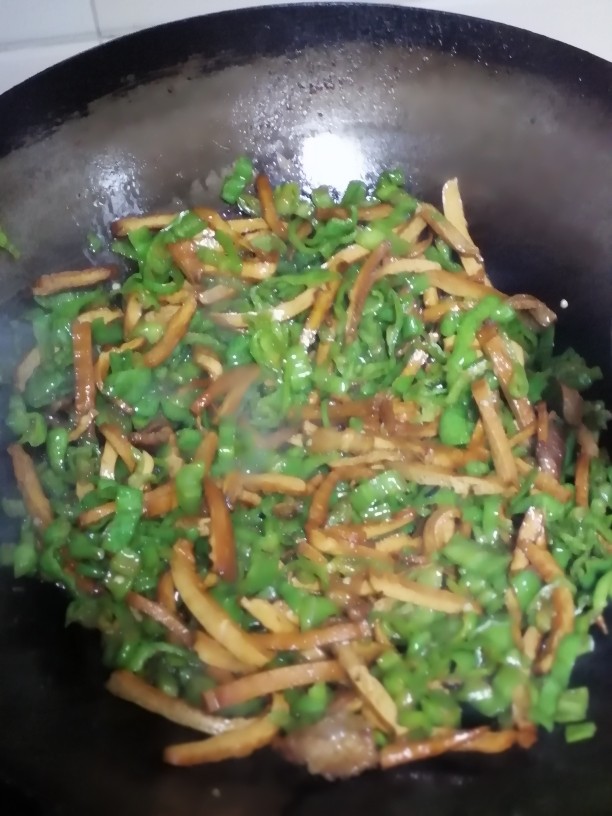 青椒香干肉丝,加入鸡精,将辣椒和香干翻炒在一起