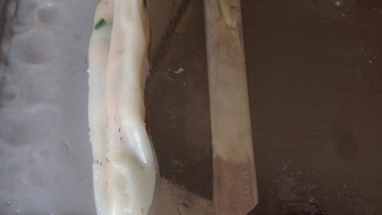 磷虾肠粉,取出,用刮板将肠粉从有虾的一边刮起来,一直卷到另一边