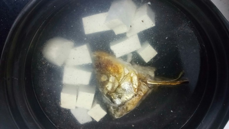 鱼头炖豆腐
,砂锅中放入适量水,放入鱼头、豆腐块,如果家里没有砂锅,可以在刚才煎鱼的铁锅里直接加水炖。