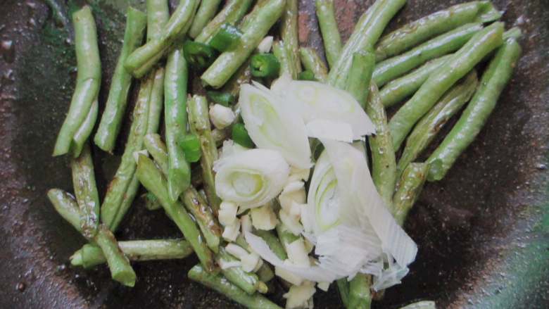 干煸豆角炒肉丝,煎至表皮微起皱微焦,放入葱花蒜末辣椒圈爆香