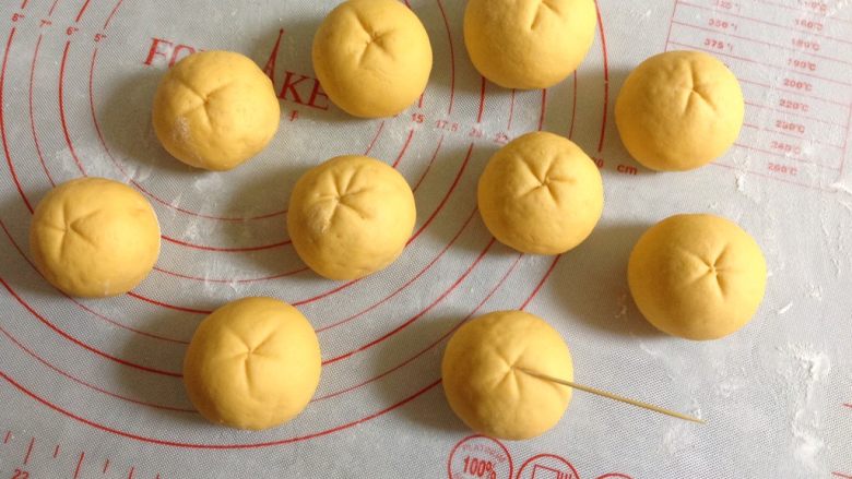 橘子馒头,全部用毛巾裹过之后,用牙签在面团顶部如图压出橘子的纹路。