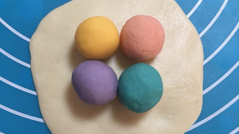 彩虹乳酪蛋黄酥,取一个油皮按扁,把四种颜色的油酥各取一个,包入油皮
