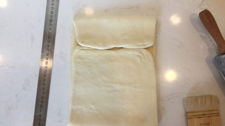 可颂,下部分向上折起约4/5,上部分向下折约1/5,如图所示。然后再直接上下对着,放入冷冻室降温约20min。注意折叠部分不可以有干粉,最好用刷子沾<a style='color:red;display:inline-block;' href='/shicai/ 156925'>水</a>湿润一下。