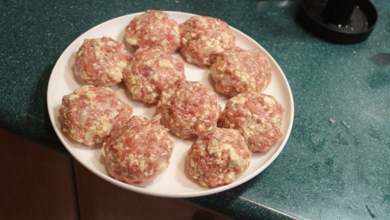 豆腐肉丸子麻婆煮,取适量的肉馅,在掌中摔打成肉丸子。