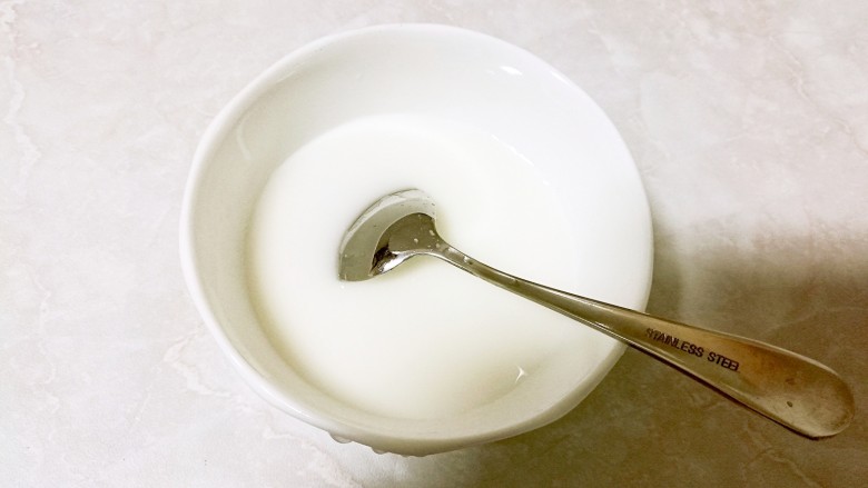 酒酿桂花粉红鸡蛋丸子,碗中放入一些玉米淀粉,倒入适量的水搅拌均匀。