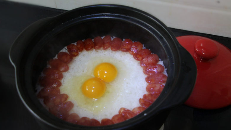 广式腊肠煲仔饭,打入两个<a style='color:red;display:inline-block;' href='/shicai/ 9'>鸡蛋</a>,盖上盖子继续焖3分钟。