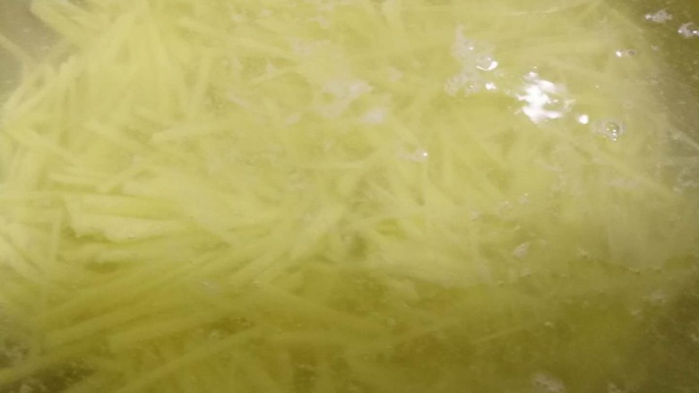 酸辣土豆丝,切好的土豆丝放入清水里浸泡,换水冼三次,洗去表面的淀粉。