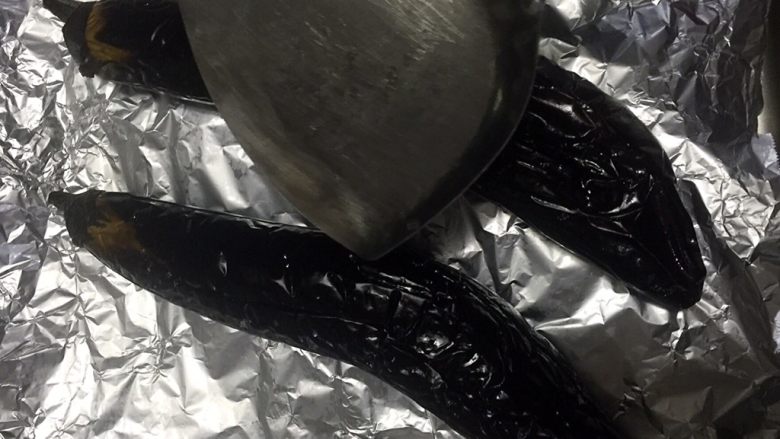 香辣烤茄子,用铲子拍一下,如果轻轻一拍就瘪了就可以了,如果不瘪就放进烤箱再烤几分钟,因为必须茄子内部完全烤熟变软才能下一步