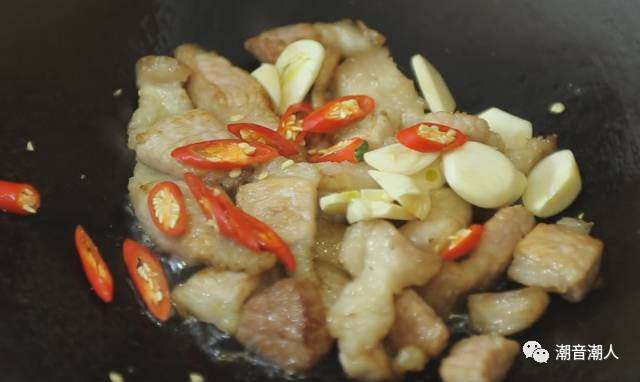 猪肉炒豆干,❥ 待猪肉颜色变成焦黄色时，依次放入蒜瓣和辣椒，翻炒均匀