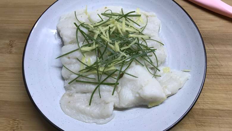 清蒸龙利鱼 ,8分钟后把蒸好的龙利鱼取出,倒去水后放上葱、姜丝。