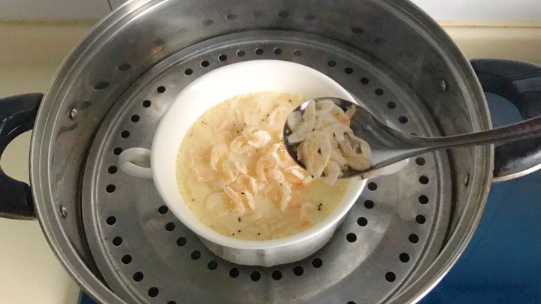 百变鸡蛋+虾扯蛋(小虾米鸡蛋羹),开盖撕开保鲜膜,再撒上一些小虾米,盖上盖子再蒸3分钟