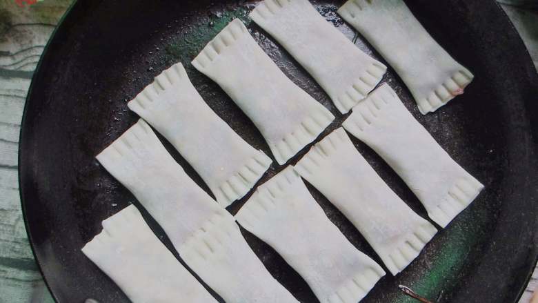 花式锅贴,煎锅中涂抹适量油,然后把锅贴紧凑的码放整齐,煎一分钟后,烹入少量清水盖严锅盖继续煎制