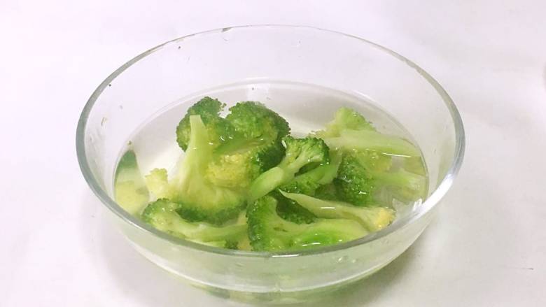 西兰花鸡肝泥,煮好的西兰花捞出,放入温水中冷却一下。
PS: 因为蔬菜煮好后直接打成泥给宝宝吃,所以这里用温水给蔬菜稍微降温而不是用冷水。 焯水后的蔬菜温度比较高,离水后与空气中的氧气接触容易产生热氧作用,营养素会流失。所以需要及时冷却降温,减少营养流失,还可以保持蔬菜翠绿的颜色。