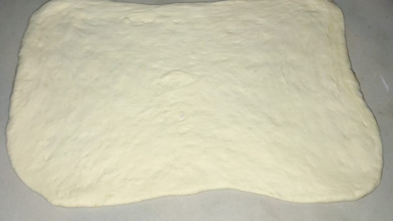 椰蓉蔓越莓圣诞花环面包,醒发好的面团,继续擀开。擀成50x35厘米的大小。