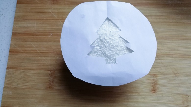 圣诞树纸杯蛋糕,将漏空纸放在撒好的蛋糕椰蓉表面上;