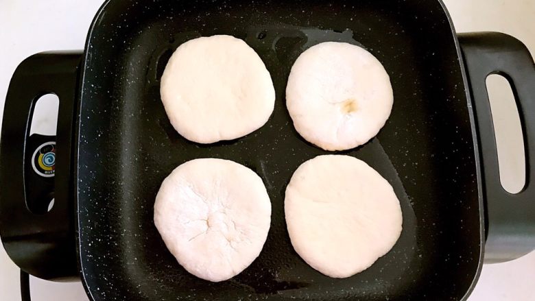 烤鸭肉夹馍,锅里加入大豆色拉油,烧五分热的时候放入饼坯,小火烙制