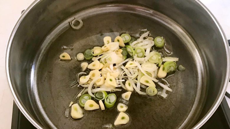 快手菜-腊肉土豆片,锅里加入大豆色拉油烧热后加入葱花和蒜片,翻炒出香味