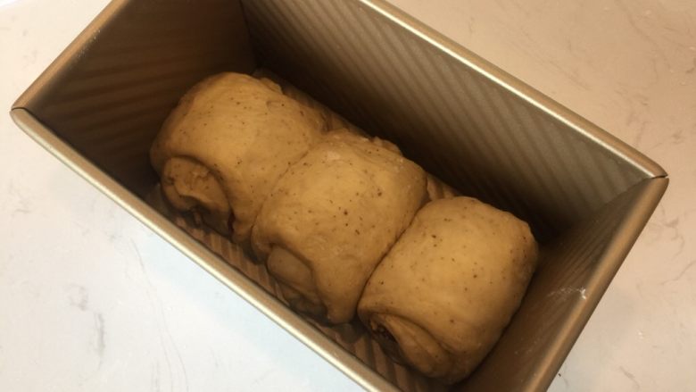 红枣养生吐司,松弛后压扁成长条舌状,卷起,入模,发酵到八分满。