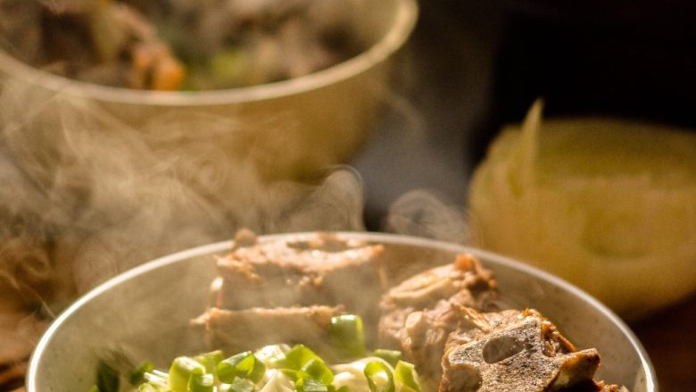 羊蝎子红汤面,把肉放入面上,撒上葱花