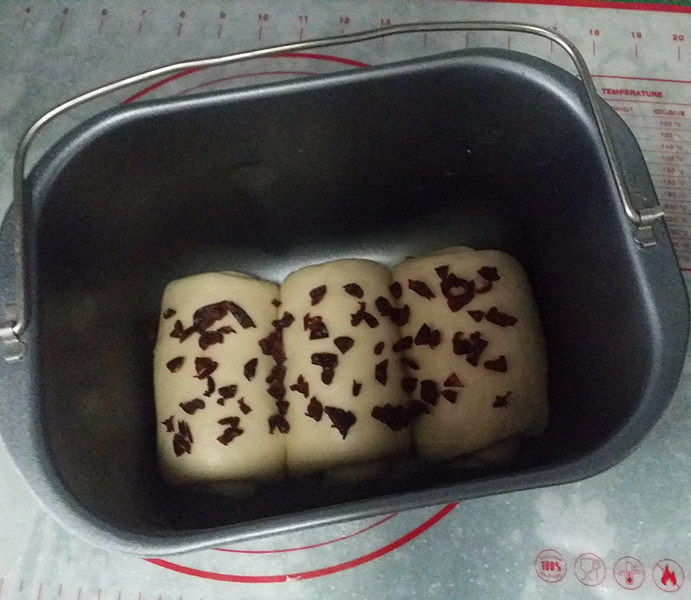 蔓越梅蛋白吐司,再自上向下卷起放入面包桶,全部卷好撒些蔓越莓粒