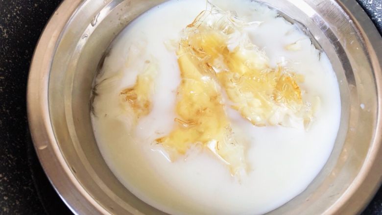 镜面百香果慕斯蛋糕,泡软后放入180g牛奶的牛奶里,隔热水加热至吉利丁片完全融化。