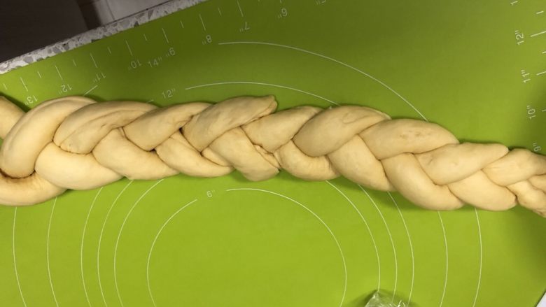 圣诞花环面包,把3条面卷头部捏合,像编辫子一样编起来,另外三条从尾部粘上继续编