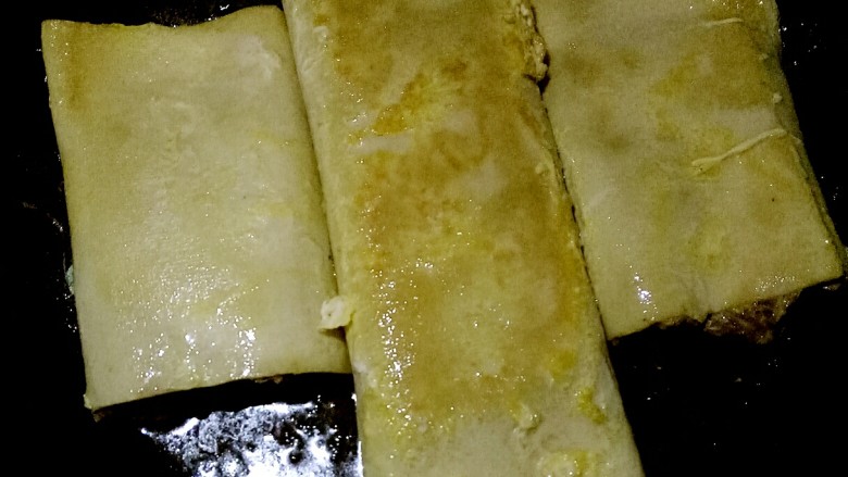 色香味俱全的豆腐皮卷煎,做法儿超级简单,营养又美味!,三分钟左右的时候,用铲子把豆腐皮卷翻面,为了防止糊锅,期间要不断的重复翻面