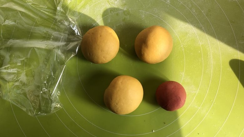 莎莉鸡豆沙包,取出发酵好的面团,分成三大一小的面团,其中小的面团加入红曲粉揉匀成橘黄色